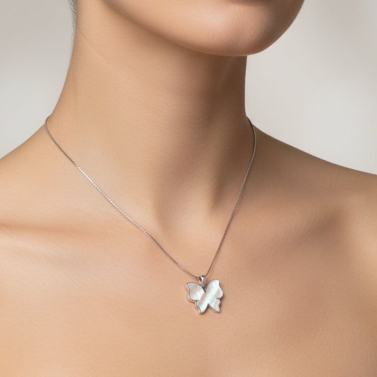 Woman wearing a silver necklace with a clover pendant against a neutral background