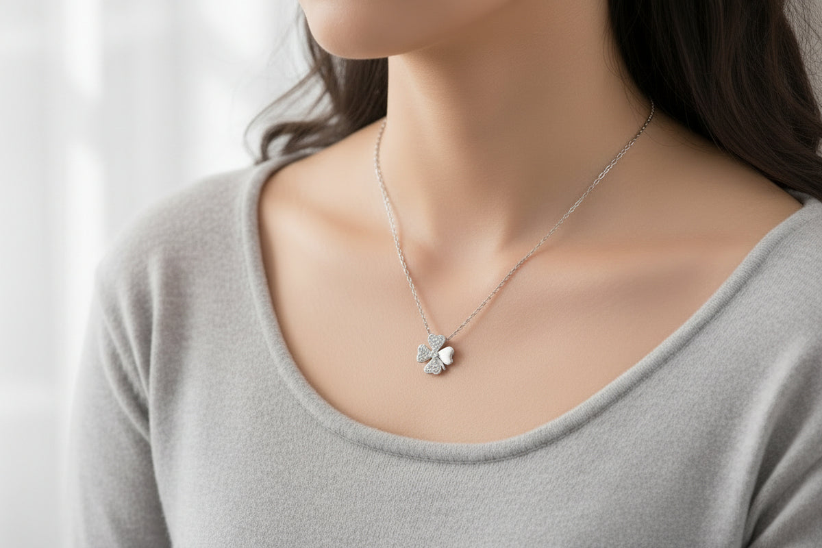 Silver necklace with a clover-shaped pendant on a wooden surface