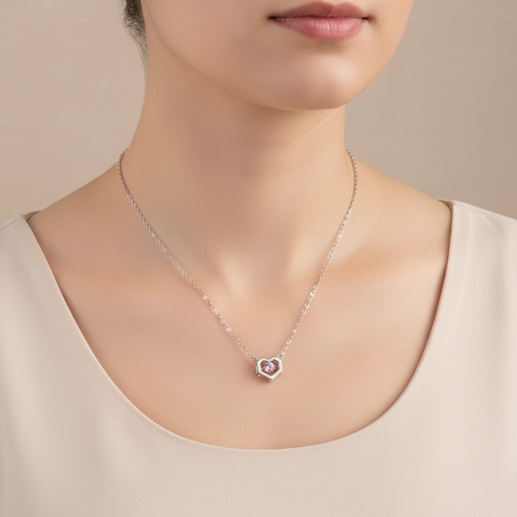 Silver necklace with a pink gemstone pendant on a wooden surface
